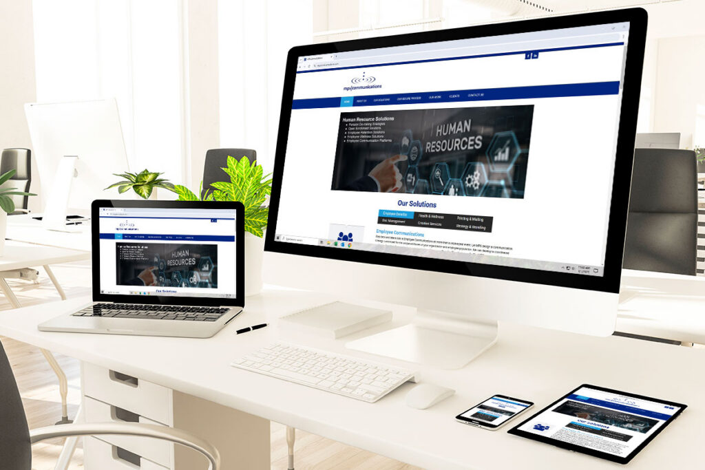 Website Design An office setting focused on a desk featuring a desktop computer, laptop, tablet, and phone. Showcasing a responsive design of the MPS Communications website.